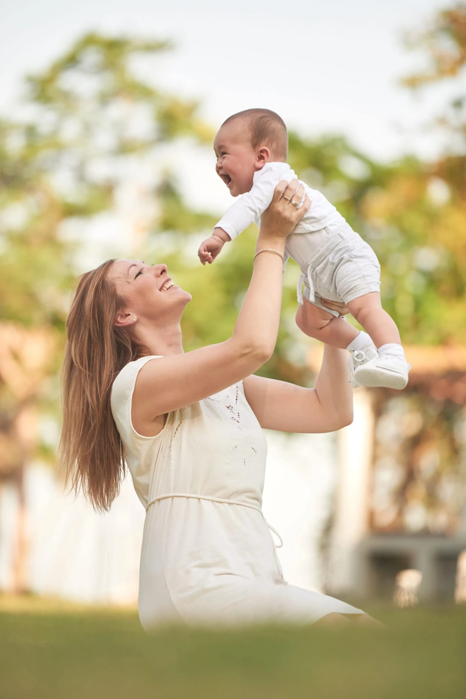 Young woman playing with her baby in summer park