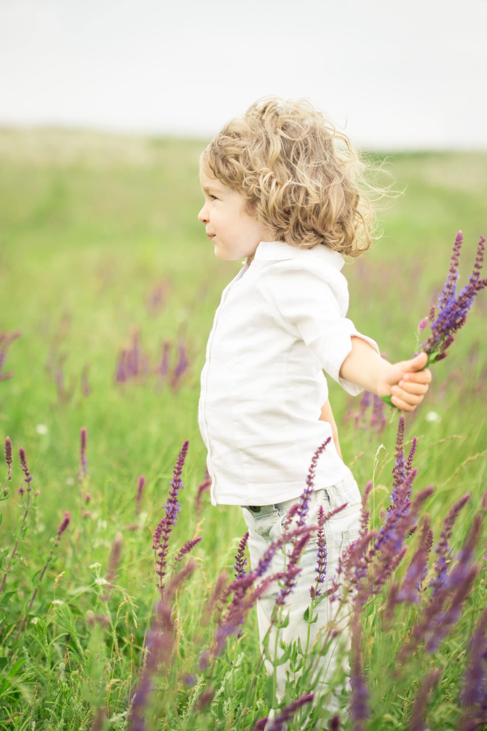 Happy child playing outdoors in spring field. Healthy lifestyles concept